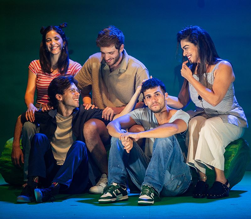 שחקני ההצגה יושבים על הבמה מחייכים