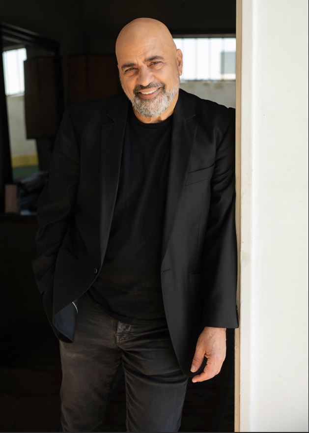 תמונה של דני רובס מחייך ונשען על משקוף דלת